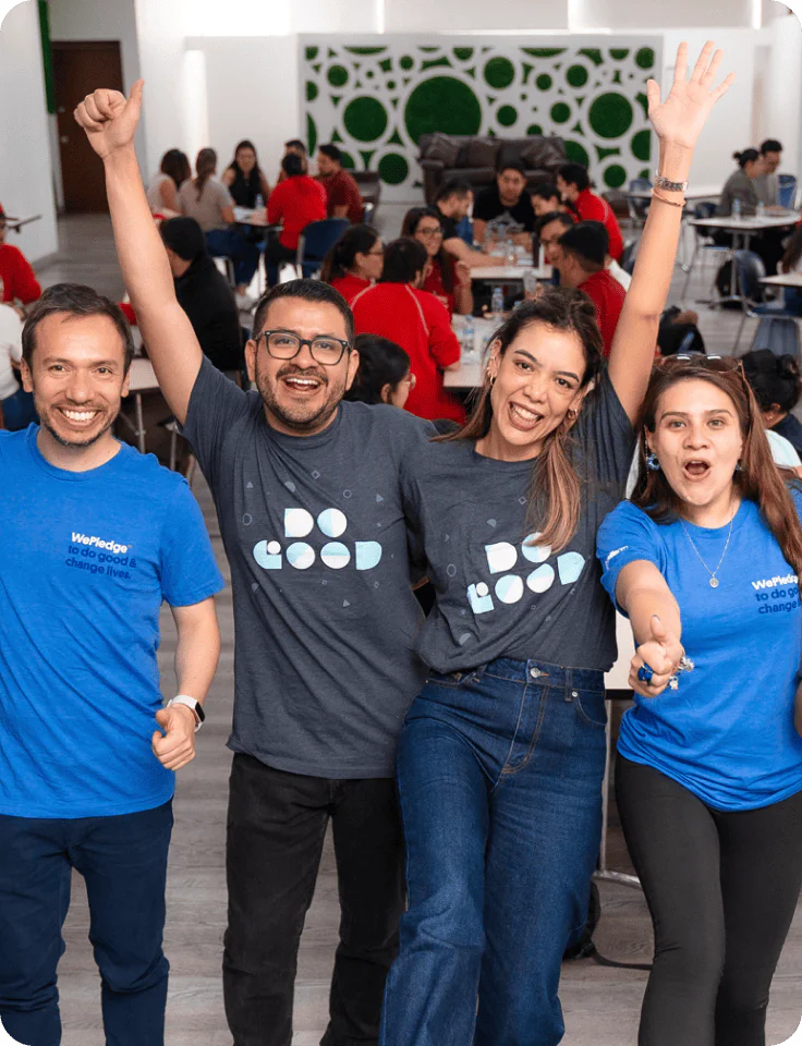 Four cheerful coworkers wearing matching shirts, celebrating in a lively office environment.