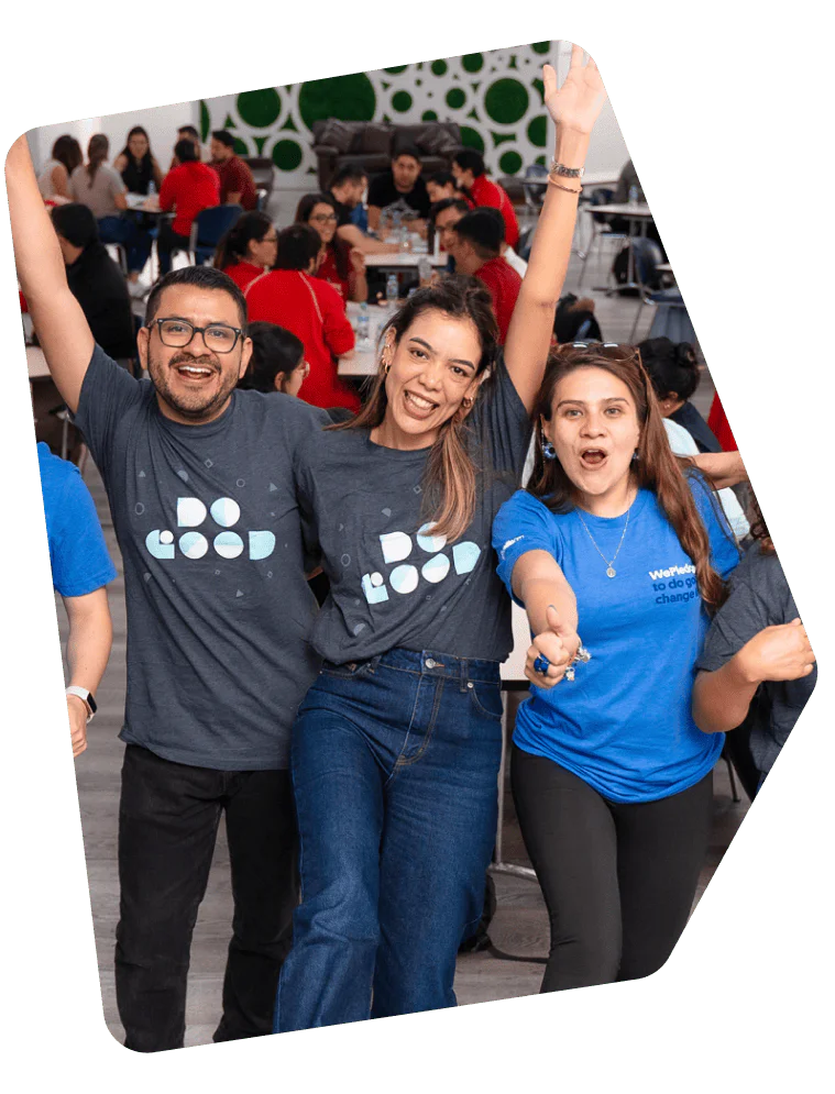 Three smiling people wearing t-shirts, one with Do Good and another with We change, at a crowded event.