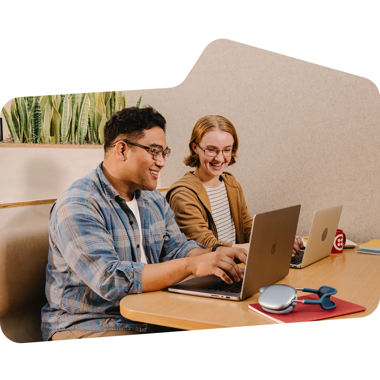 Two co-workers working together on laptops at a table.