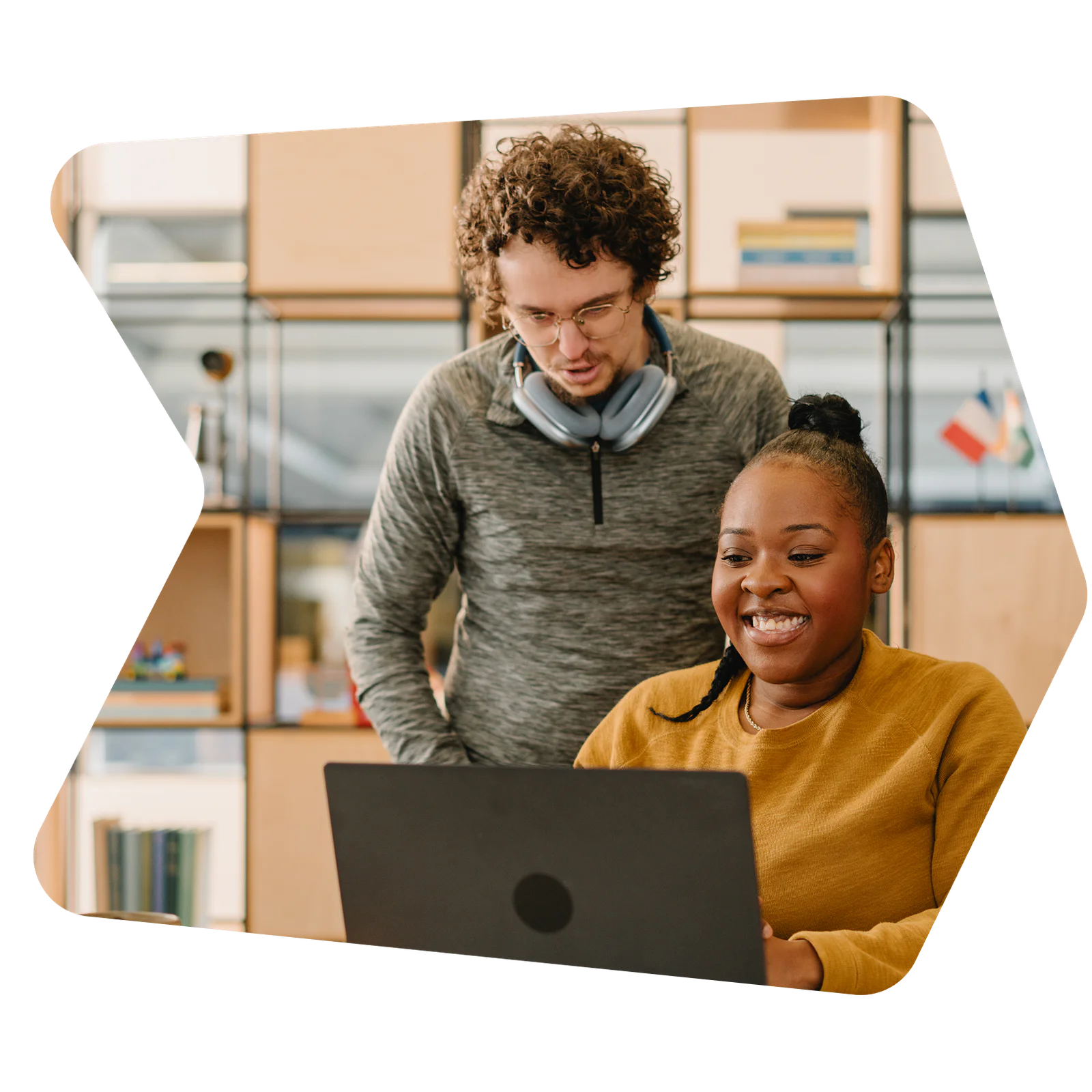 Man and woman smiling while working together on a laptop in a modern office setting