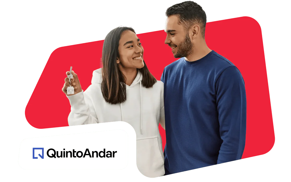 Smiling couple holding keys in front of a red background with QuintoAndar logo.