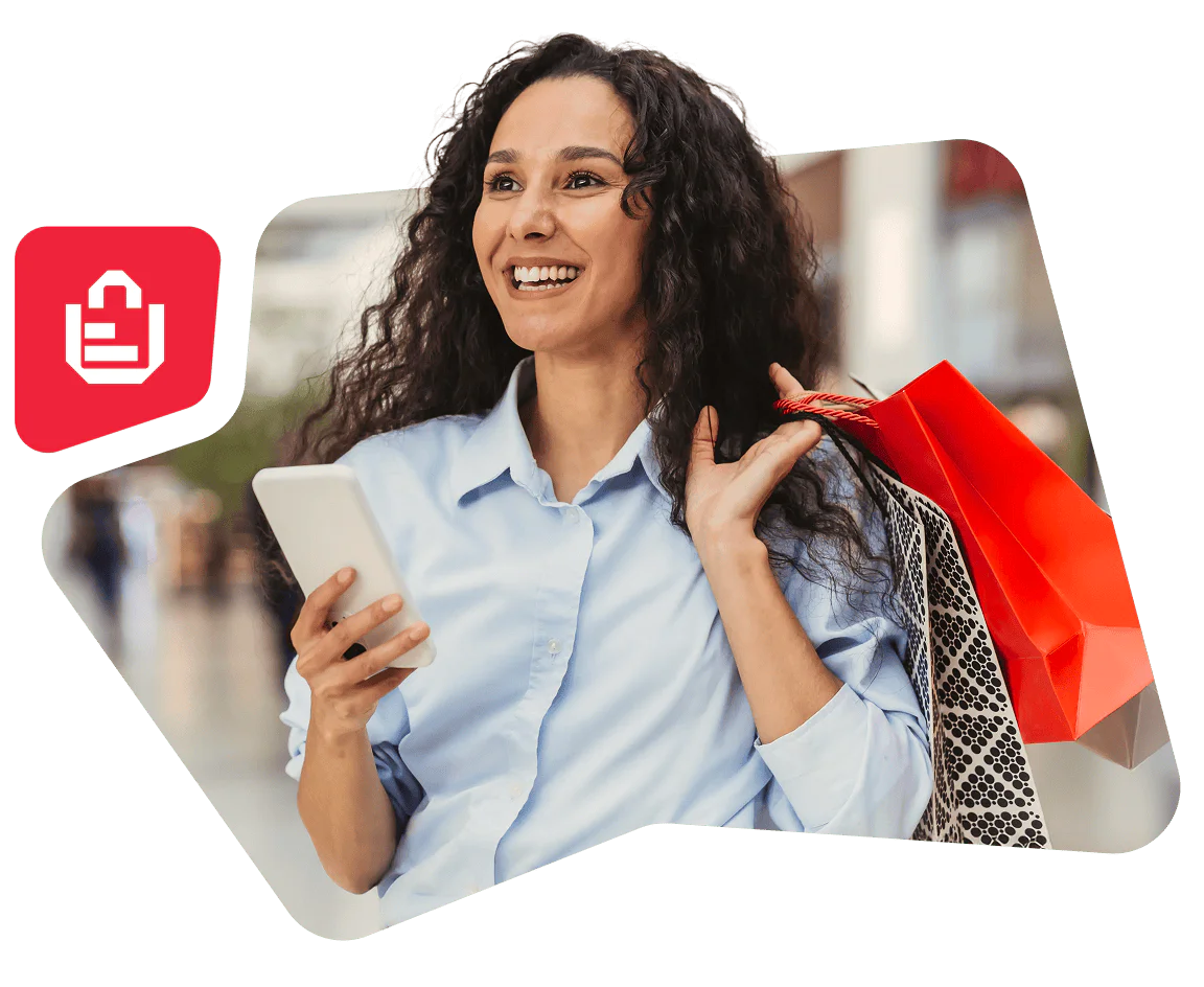 Smiling woman holding shopping bags and using smartphone outdoors.