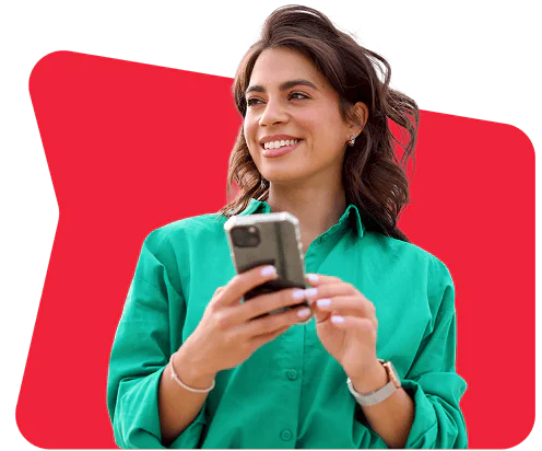 Smiling woman in a green shirt holding a smartphone with a red background