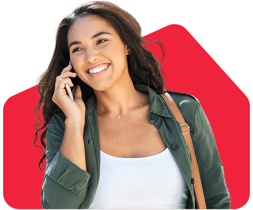 Smiling woman talking on the phone against a red background, wearing a green jacket and white top.