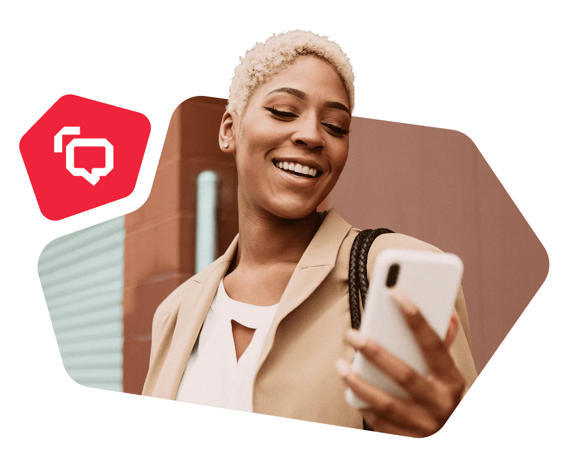 Woman in a beige blazer smiling while looking at her smartphone.