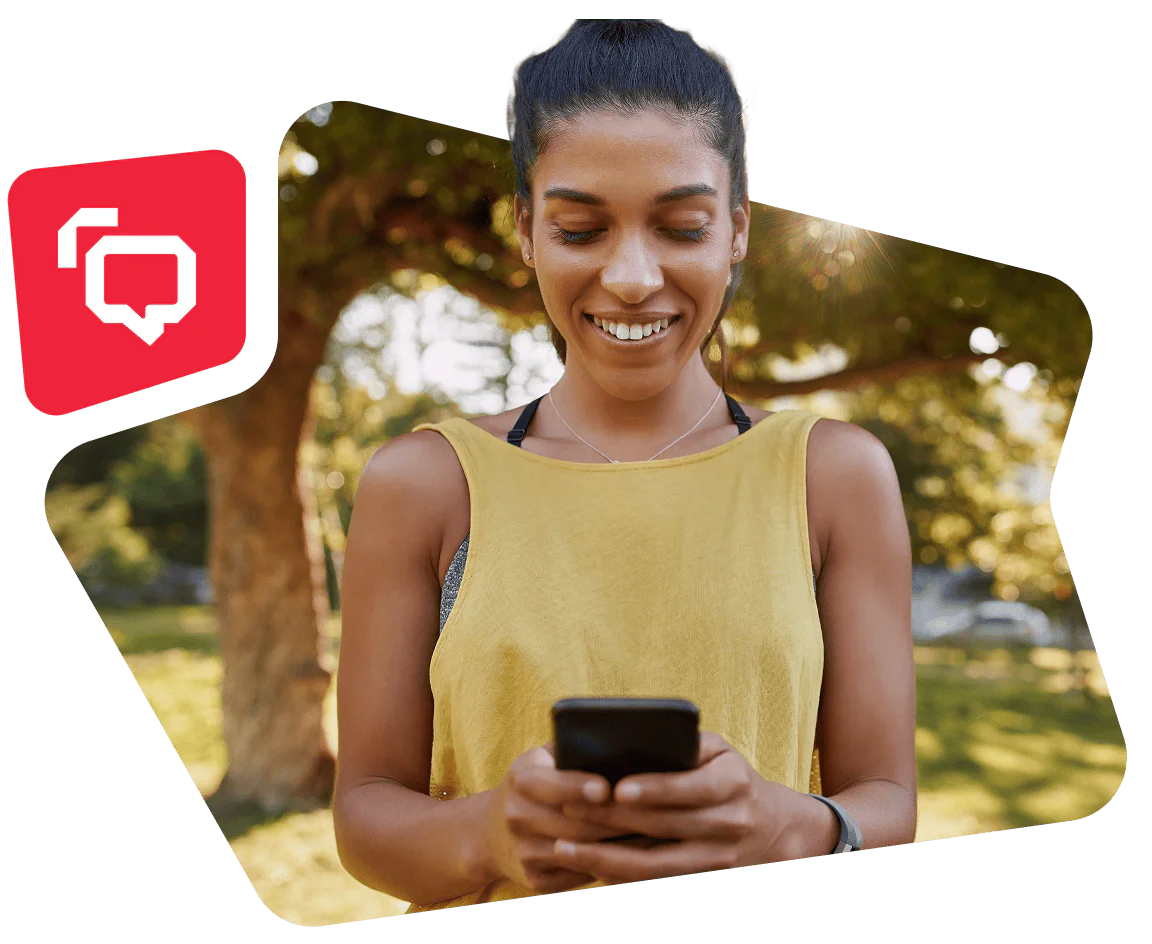 Woman in yellow top smiling and looking at her smartphone in a sunny park