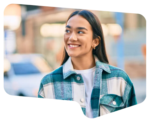 Woman in green checkered jacket smiling outdoors with blurred street background