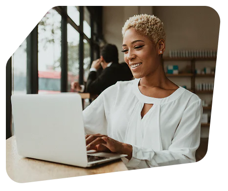 Smiling woman using a laptop at a cafe.