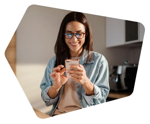 Woman with glasses smiling and using a smartphone indoors