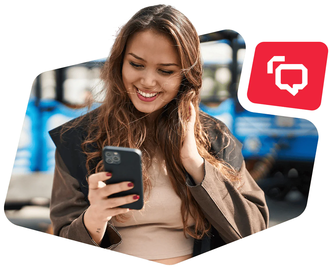 Woman smiling and touching her hair while looking at a smartphone.