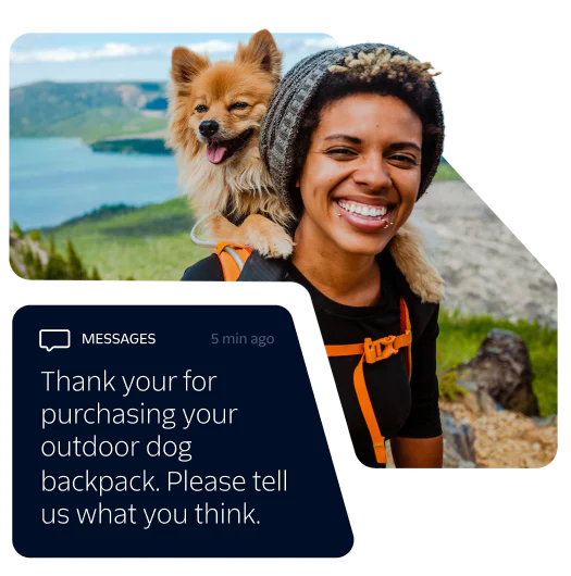 Smiling woman with a dog in a backpack hiking in a scenic outdoor area.