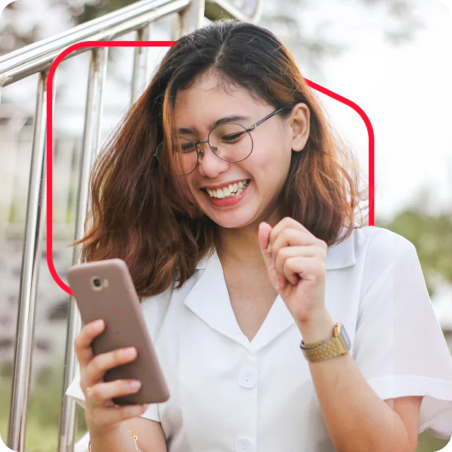 Young woman with glasses smiling while looking at her smartphone.