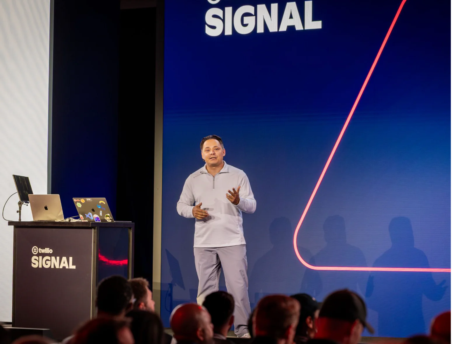 Man speaking on stage at Twilio SIGNAL event with logo and audience in view.