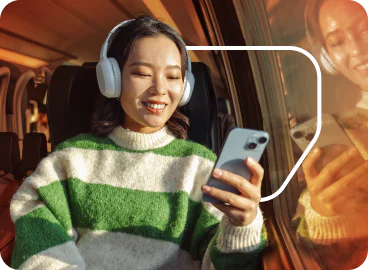 Woman wearing headphones sitting on a couch using a phone