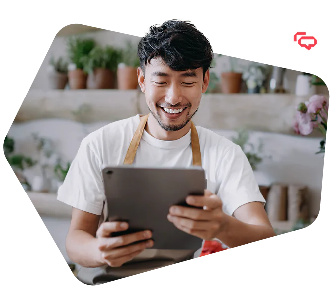 Florist smiling while using a tablet in a flower shop with flowers and laptop on the counter