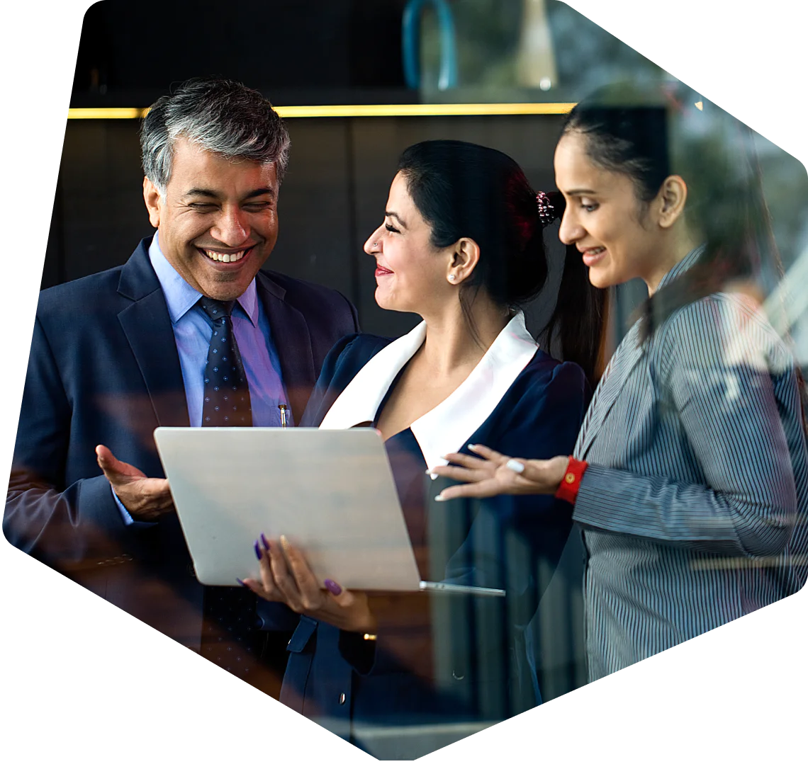Three business professionals smiling and looking at a laptop screen together.