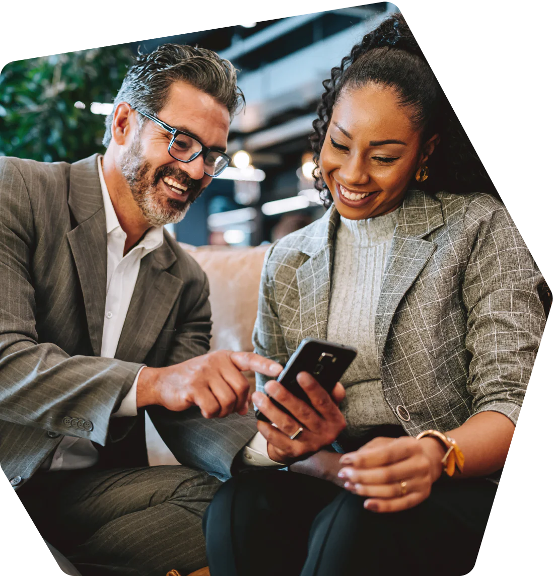 Woman in a plaid blazer sitting and smiling with a tablet in her hands