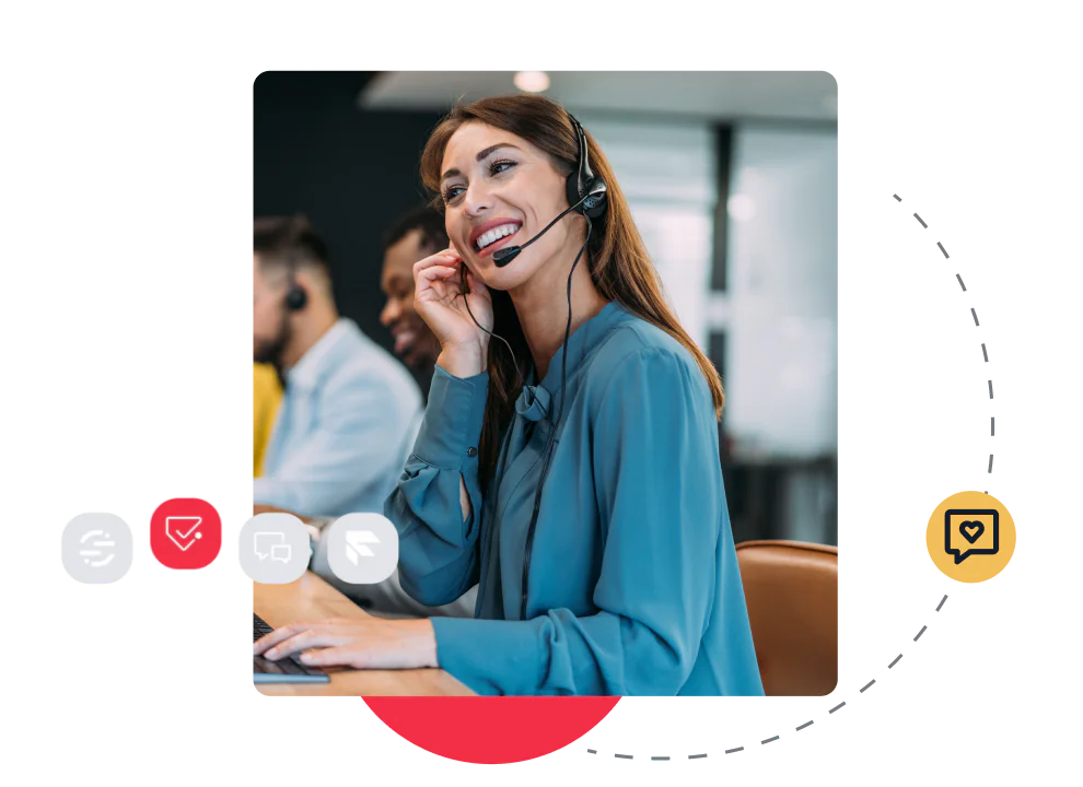 Woman in headset smiling at desk with colleagues in the background