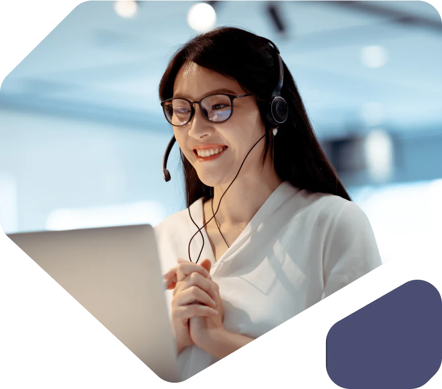 Smiling woman wearing a headset and glasses working on a laptop