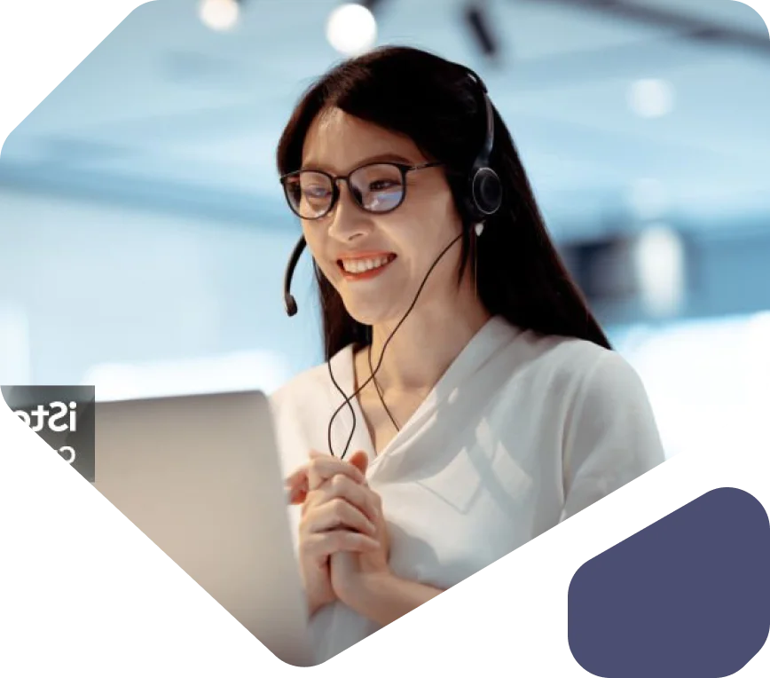 Woman Wearing Headset Smiling During a Video Call Woman with glasses and headset smiling while looking at her laptop.
