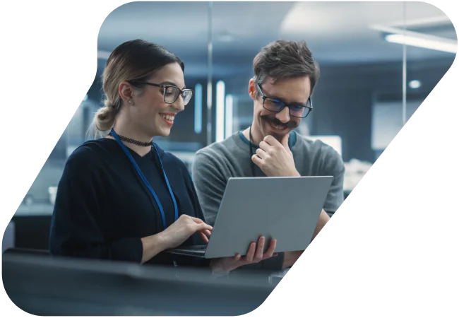 Two colleagues discussing something on a laptop screen in an office setting