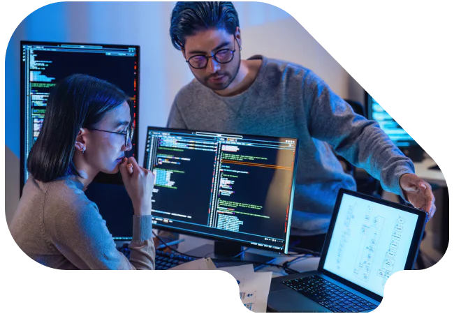 Two programmers working on code and diagrams on multiple screens.