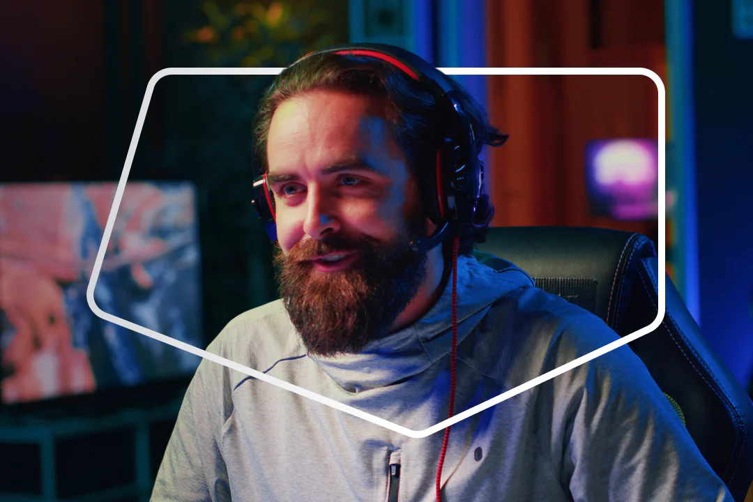 Man with headphones and microphone sitting in a gaming chair streaming in a dimly lit room.
