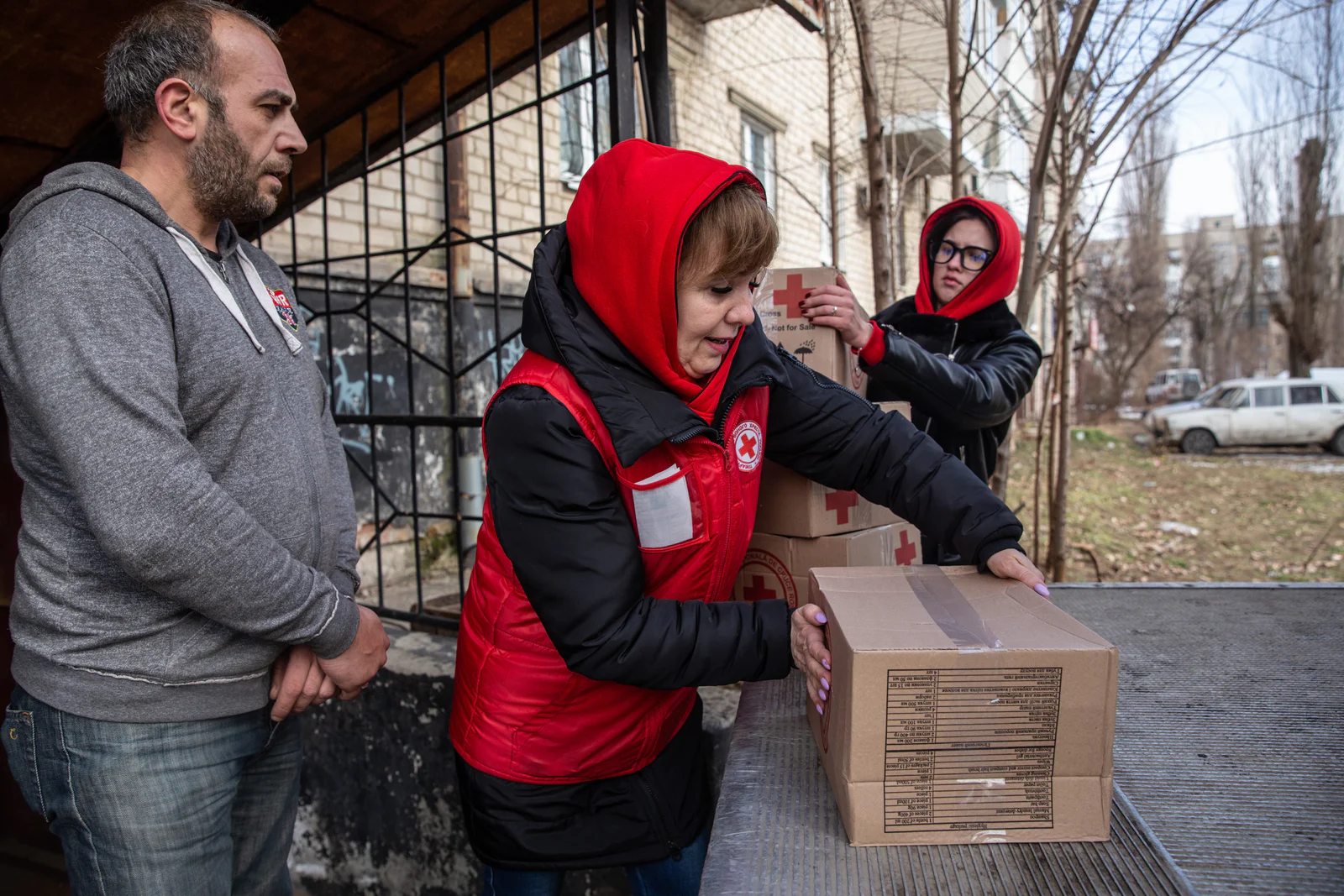 Volunteers in red jackets unloading boxes from a truck for distribution