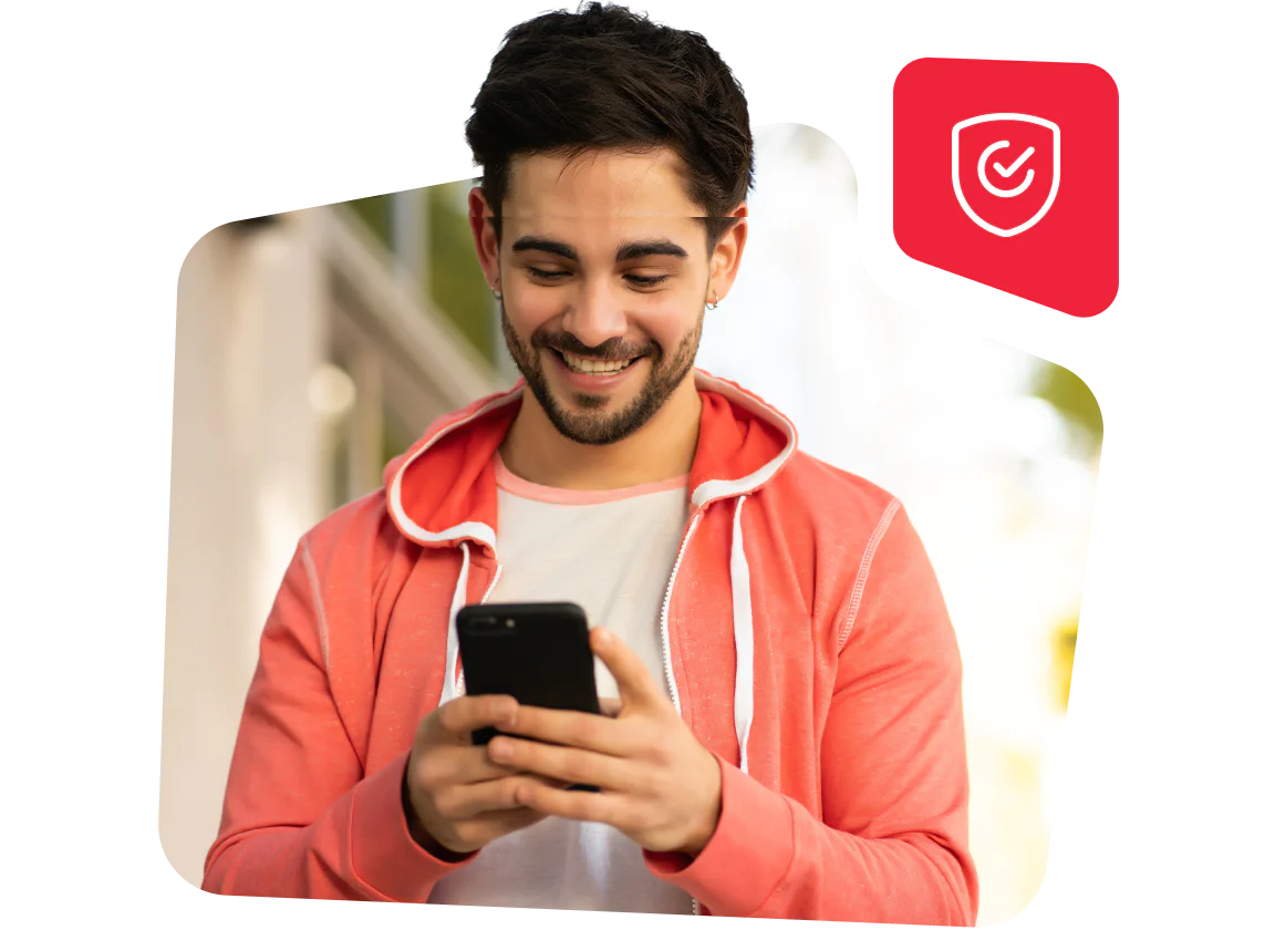 Smiling man in a pink hoodie looking at his phone, with a red security shield icon in the background.
