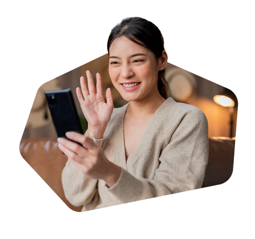 Woman smiling and waving at her smartphone during a video call.