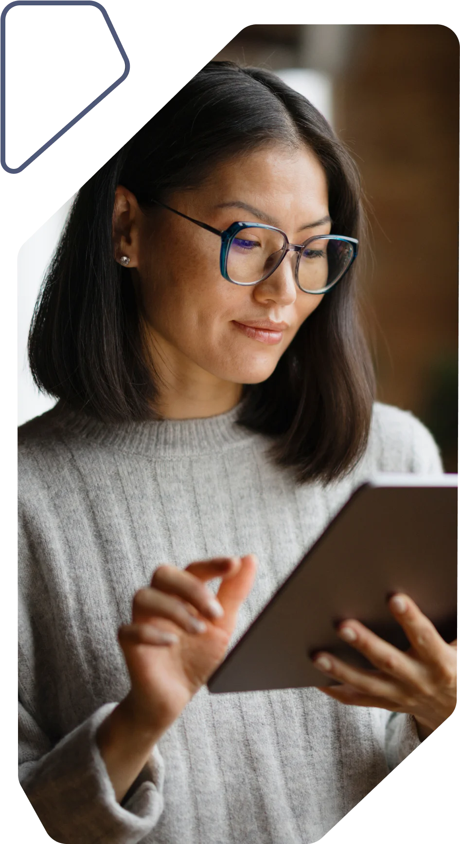 Woman with glasses and gray sweater using a tablet device.