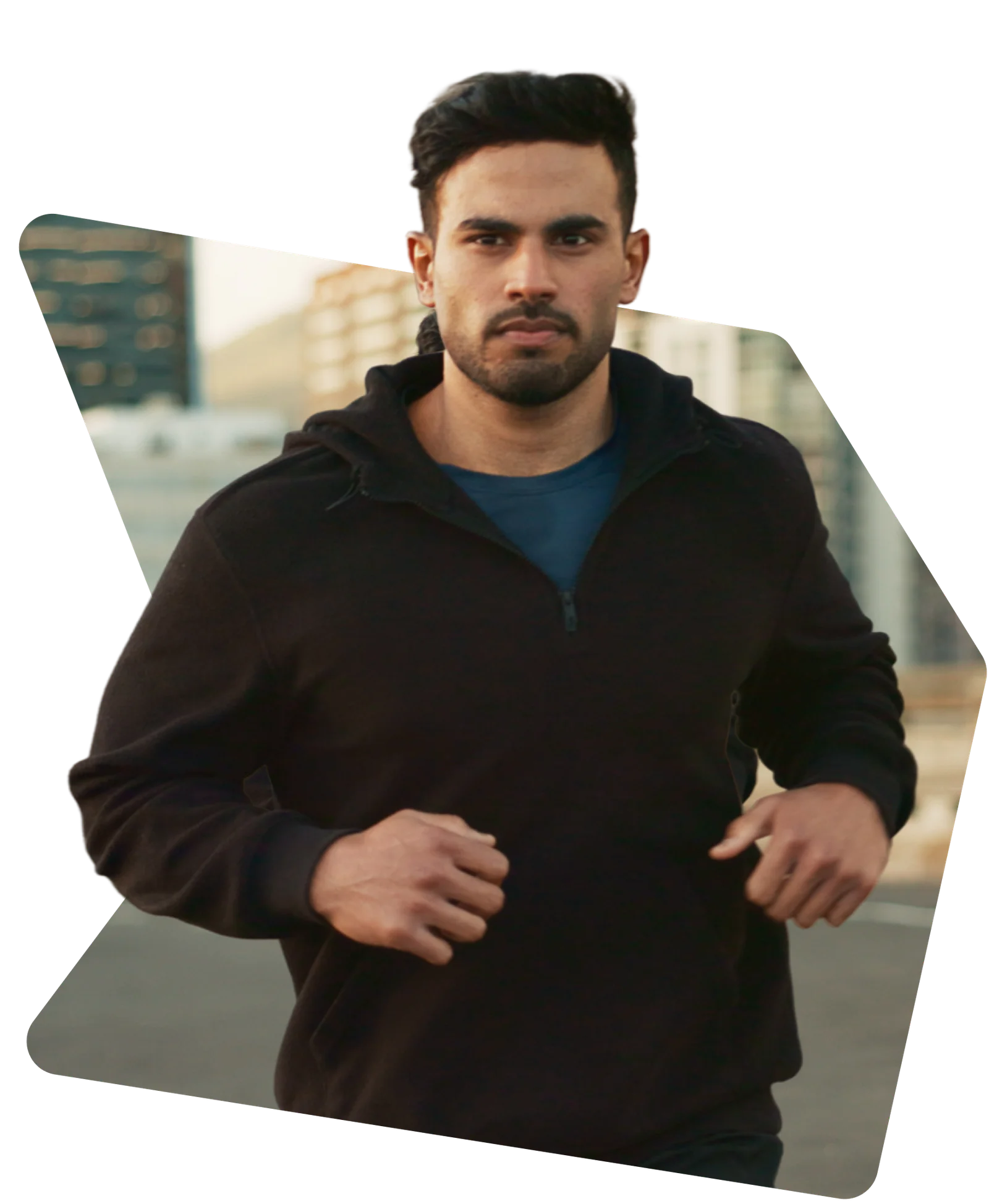Man in a black hoodie jogging outdoors with a focused expression.