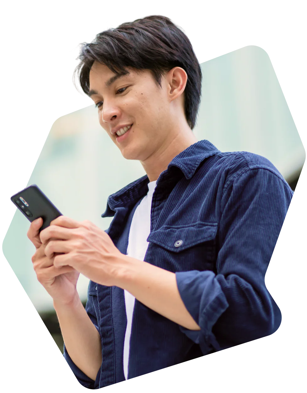 Young man smiling while looking at his smartphone.