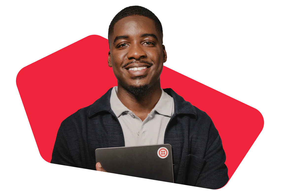 Man Smiling and Holding a Laptop on a Red Background Smiling man holds a laptop in front of a red geometric background.