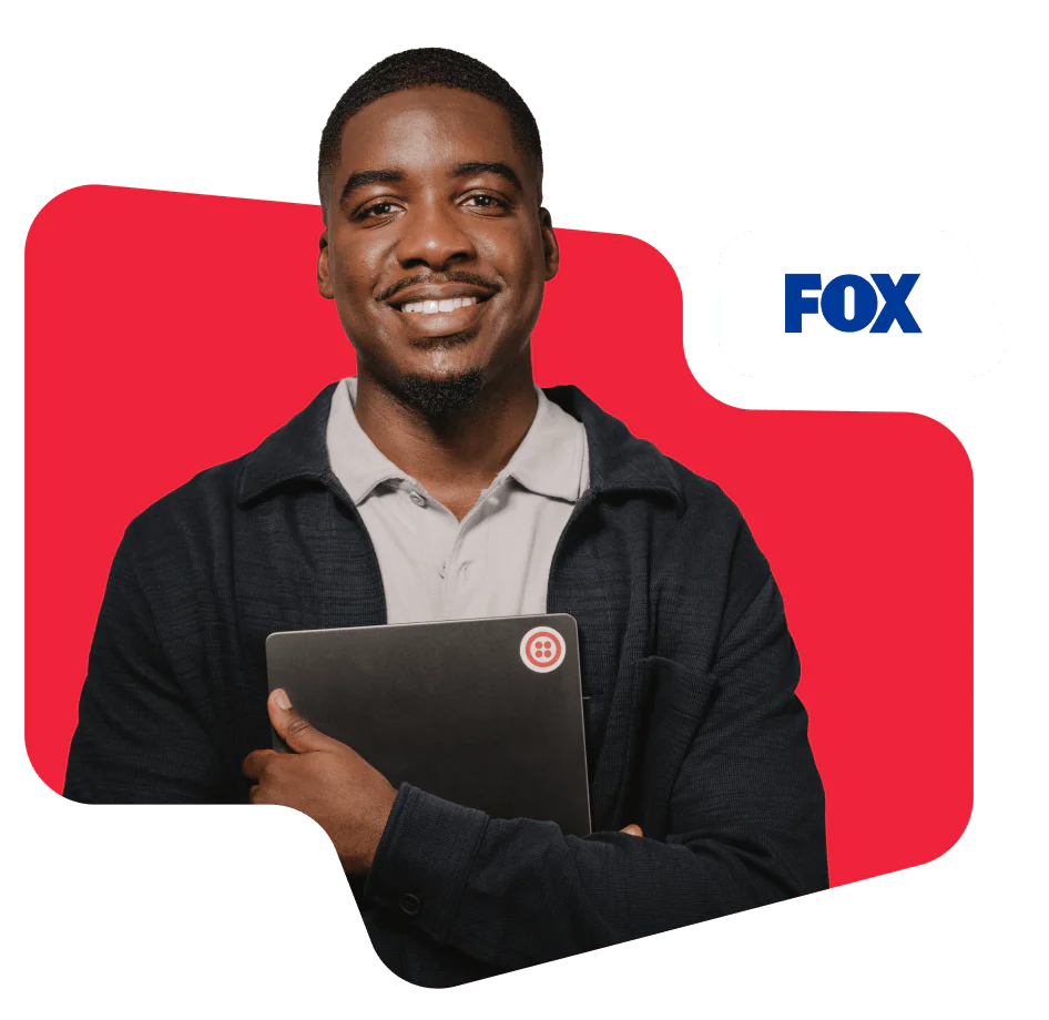 Man smiling and holding a laptop in front of a red background with FOX logo.