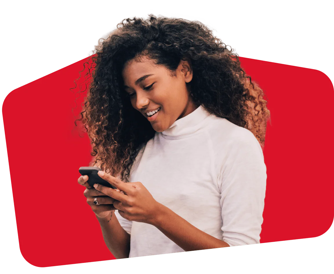 Woman looking at smartphone and smiling, against a red background.