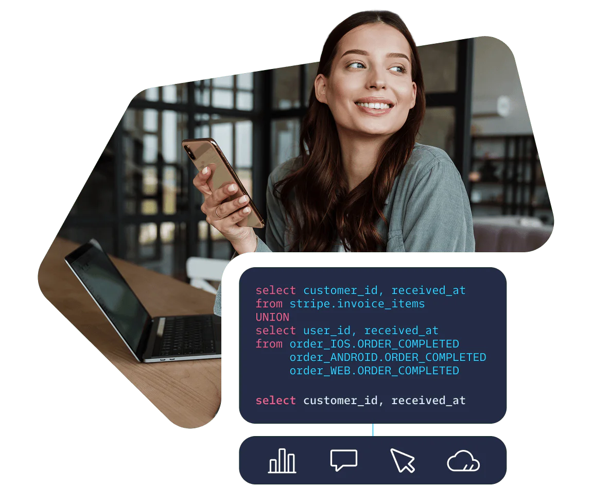 Smiling woman holding phone, sitting by a laptop with SQL code displayed on the screen.