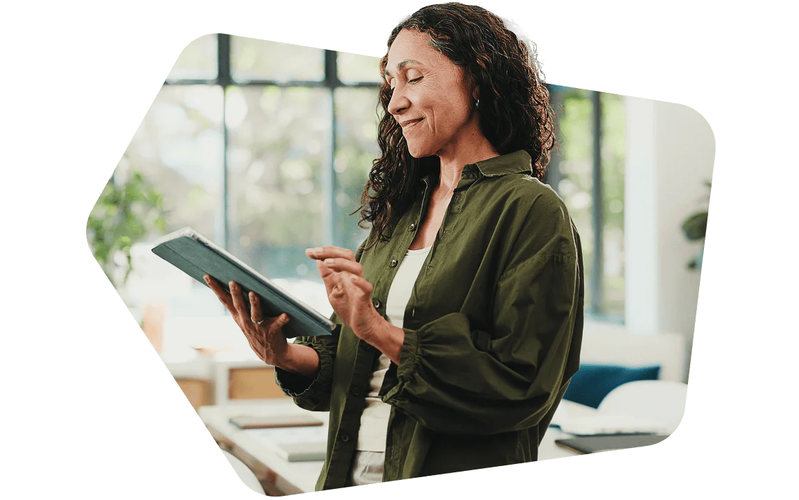 Woman in green shirt smiling and using a digital tablet indoors