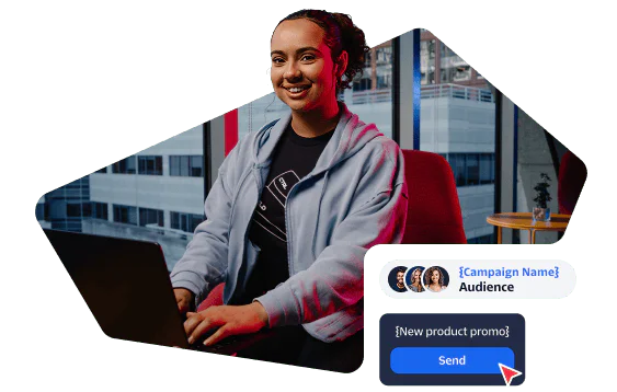 Woman sitting at desk, smiling, using laptop with social media marketing campaign graphics
