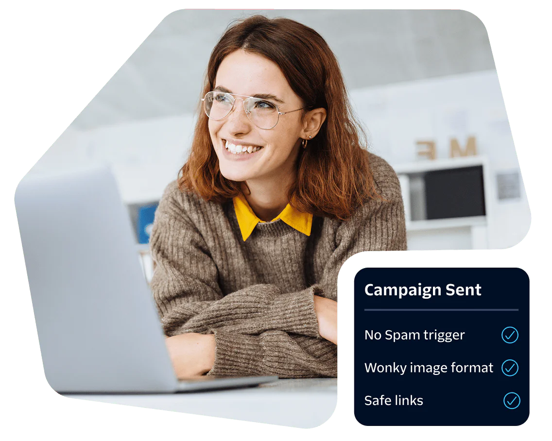 Woman wearing glasses smiling at a laptop with displayed campaign metrics.