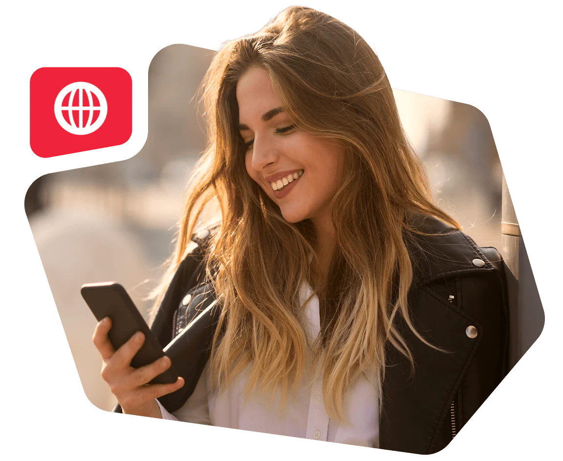 Woman with long hair in leather jacket smiling while using a smartphone outside
