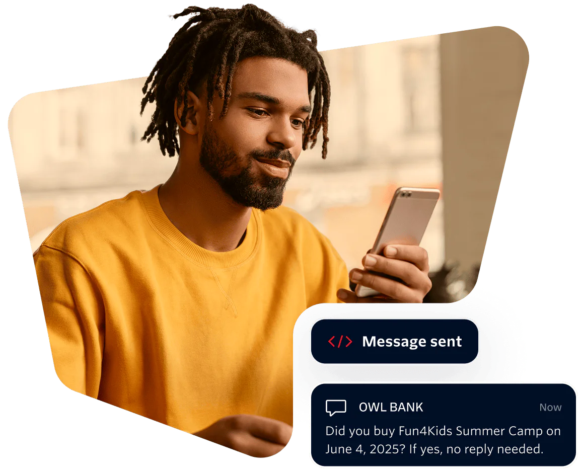 Man in yellow shirt looking at phone with a message from Owl Bank about a summer camp purchase.
