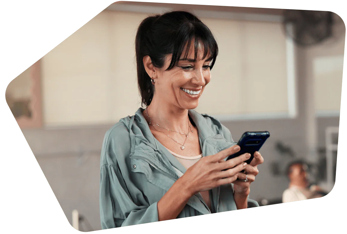 Woman smiling while looking at her smartphone indoors