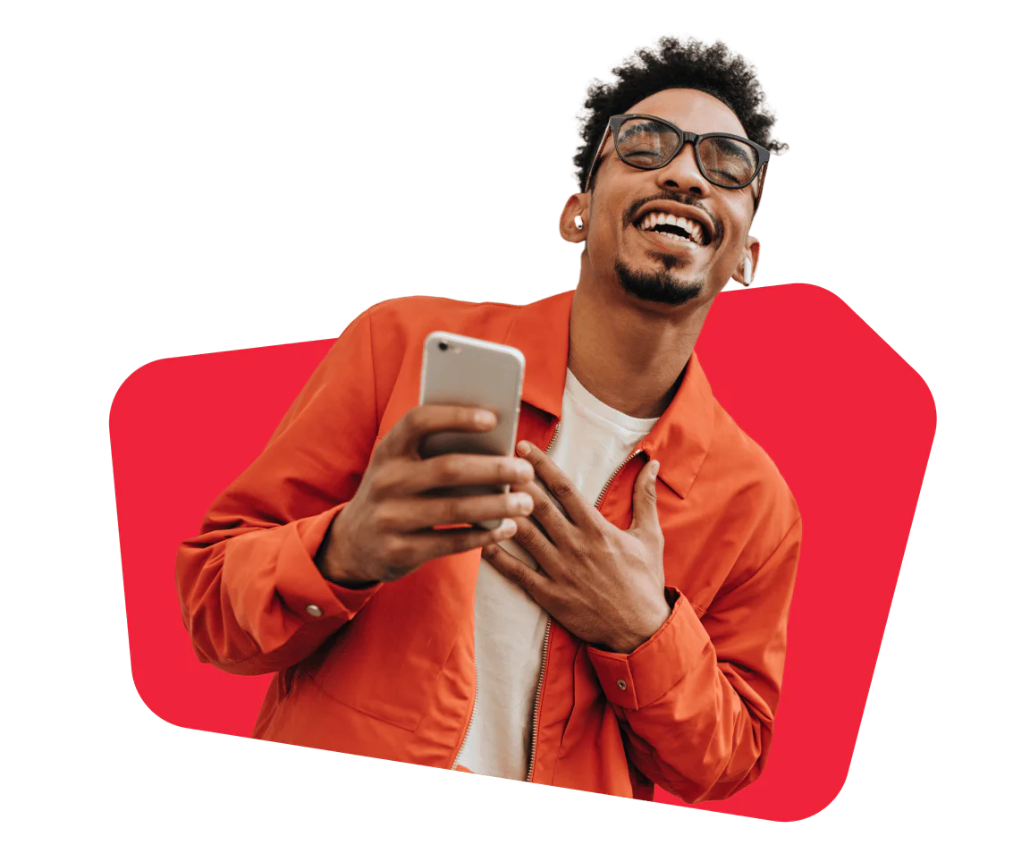 Smiling man in an orange jacket holding a smartphone Man wearing glasses and orange jacket smiling while holding a smartphone