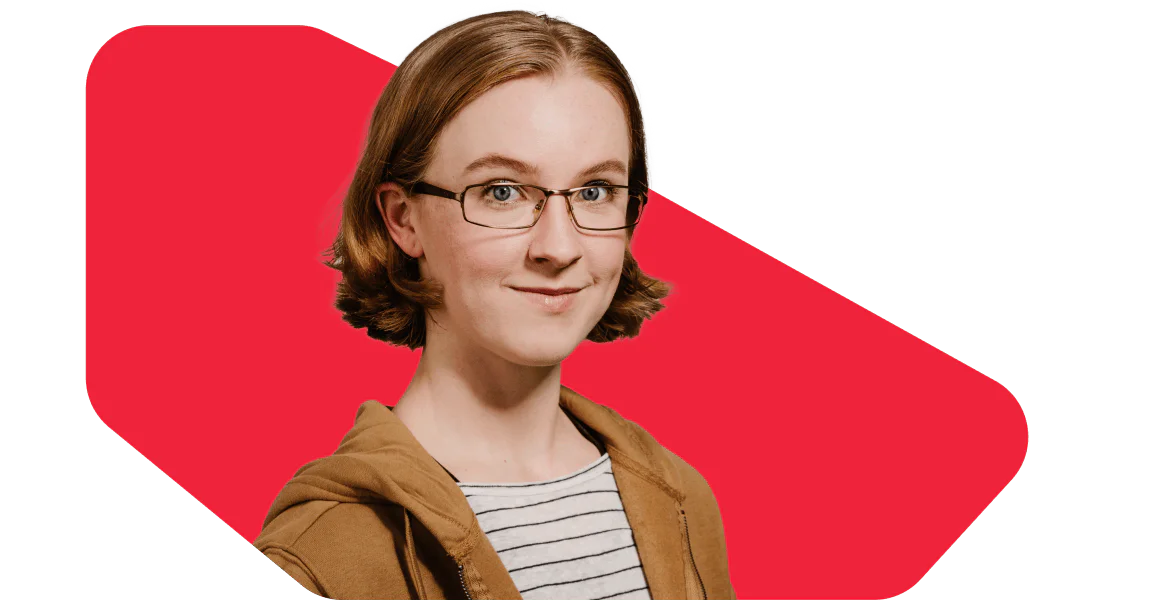 Young Woman with Glasses and Brown Jacket on Red Background Young woman with glasses and a brown jacket standing in front of a red backdrop, smiling.