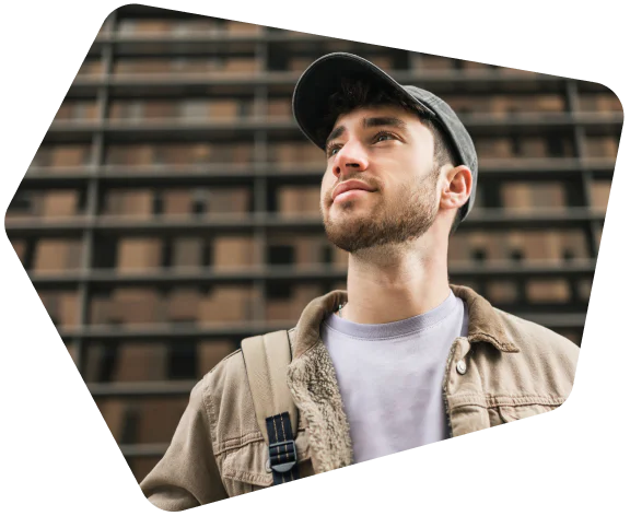 Man in a cap and jacket looking up with a building in the background