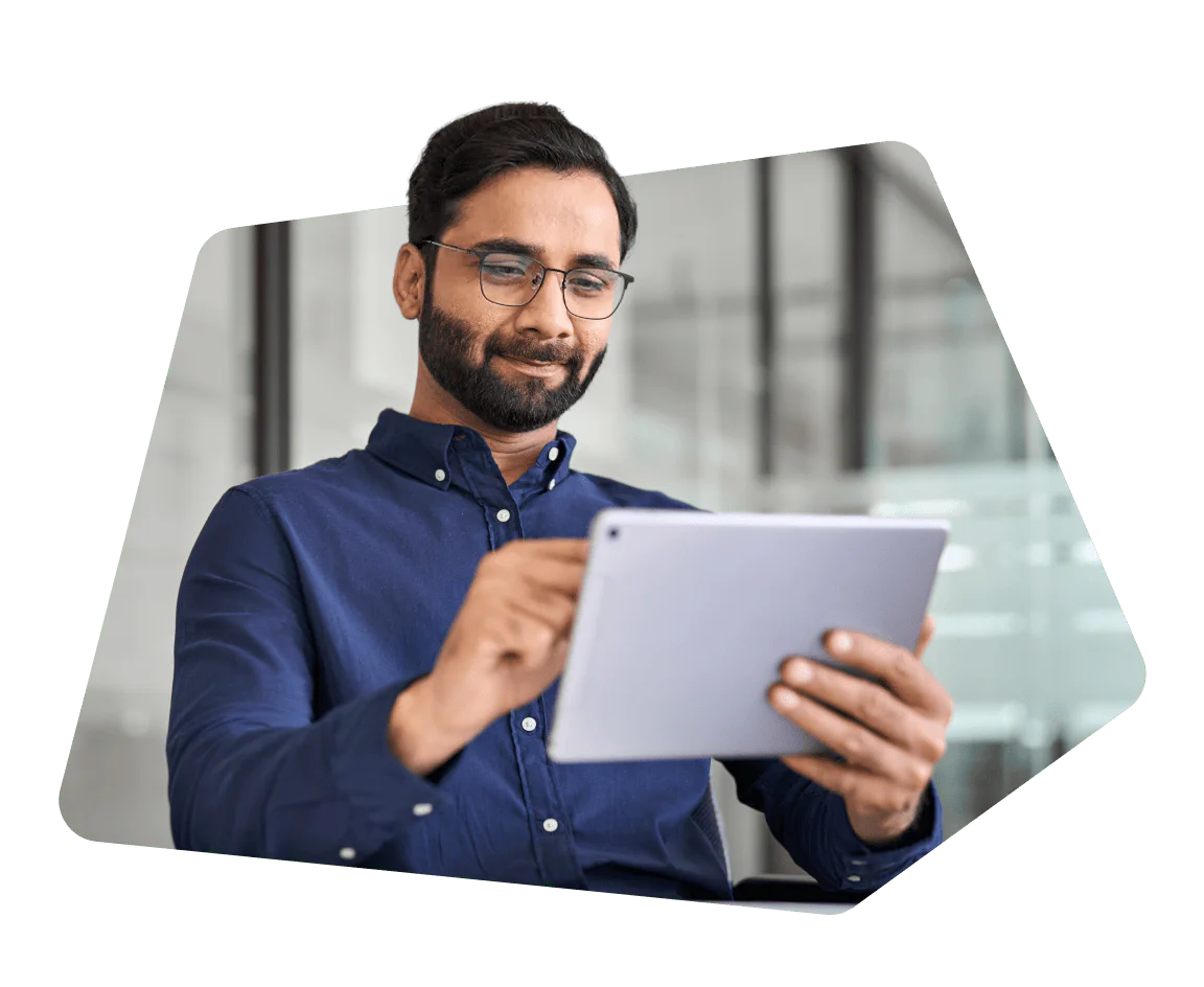 Man with glasses using a tablet while seated in an office environment.