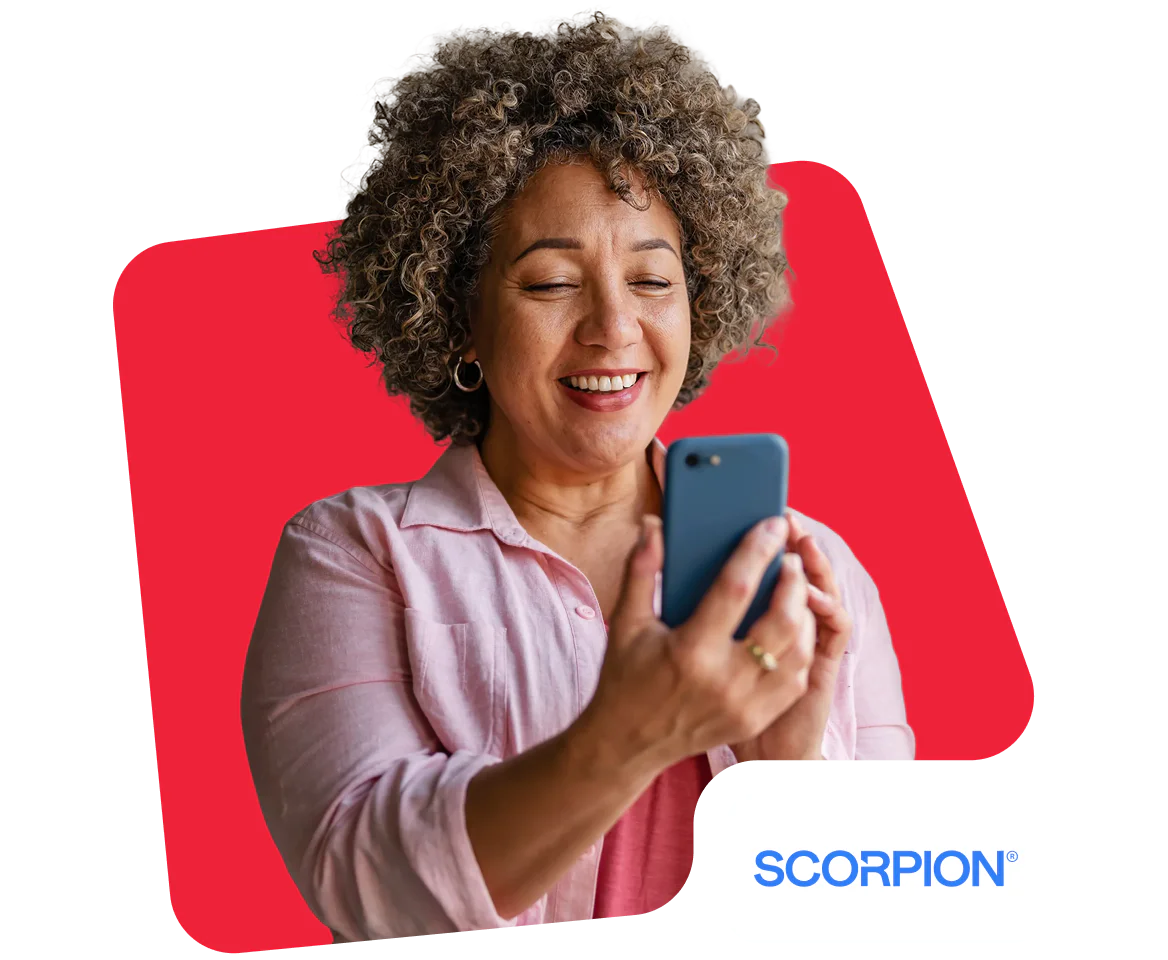 Smiling woman with curly hair using a smartphone against a red background.