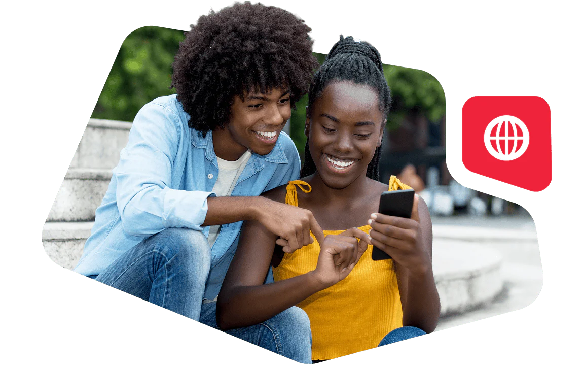 Smiling couple looking at a smartphone while sitting outdoors.
