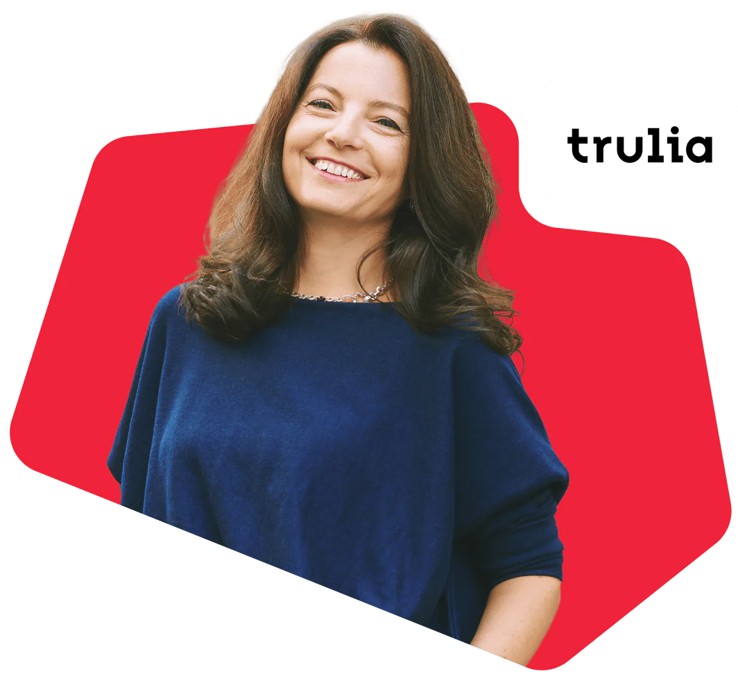 Woman in blue sweater smiling with Trulia logo on a red background